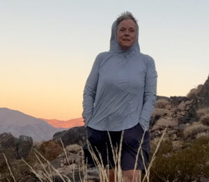 Julia Clothier stands in front of rock formations with sunset lighting