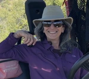 Staff member Michelle Cooper, with hat on, sits in an ATV