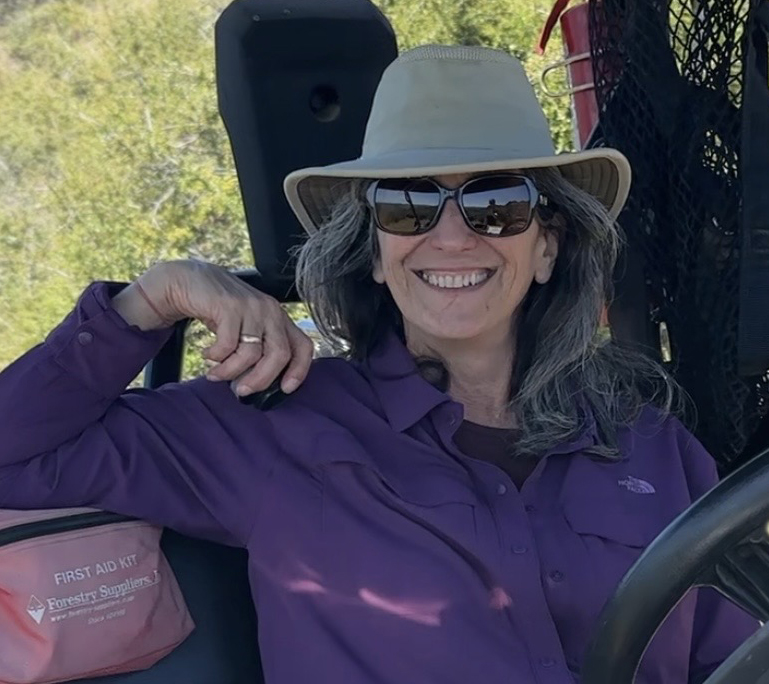 Staff member Michelle Cooper, with hat on, sits in an ATV