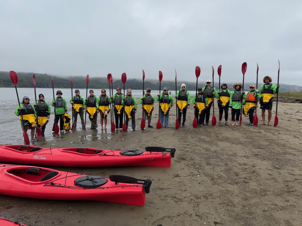 people standing next to kayaks on Tomales Bay