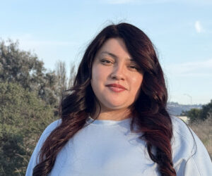 close-up of Keyra Sanchez standing among trees and shrubs