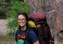 close up of Andrea Steig wearing a backpack near a rock face